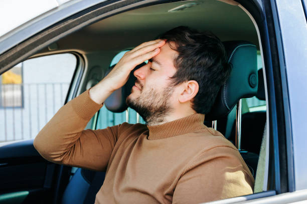 istock chauffeur man with pain and headache inside a car. 1453676946