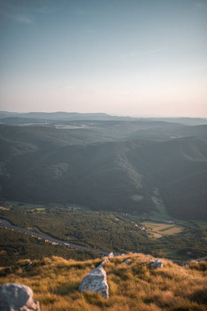 Road leading to a town in a valley between the mountains. Peaceful landscape from a hiking viewpoint.