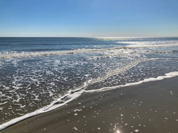 istock Bright sunlight on the waves at the waters edge 1453680988