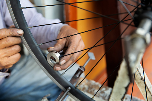 A view of a bike mechanic's hands as he works on the wheel of a bicycle.