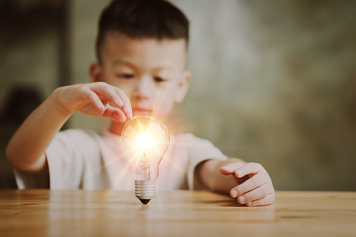Boy kid Child with a bright light bulb. Concept of Ideas for presenting new ideas Great inspiration and innovation new beginning.