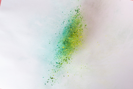 blue green yellow powder explode on pink background captured in high speed