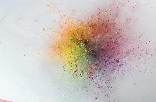 blue green yellow powder explode on pink background captured in high speed
