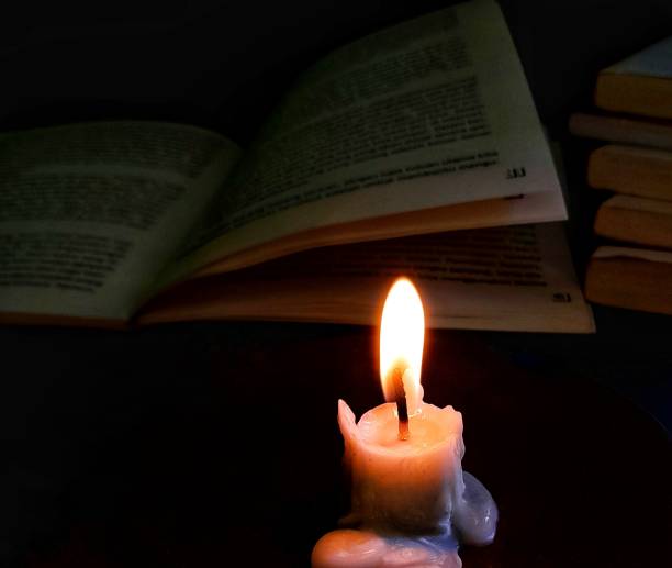 istock a burning candle illuminates the reading book 1453699311