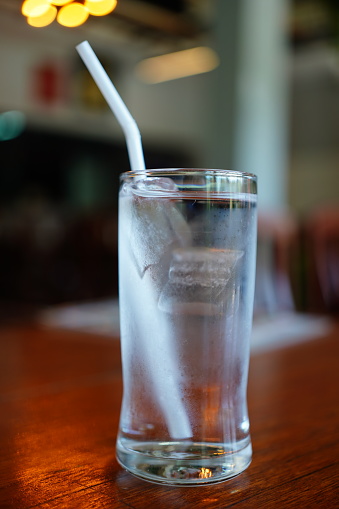 Glass of water with ice cubes on table