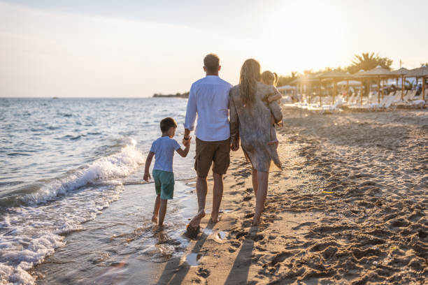 istock Beautiful family holding hands walking on the beach 1453723826