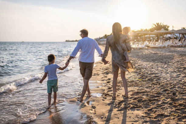 istock Beautiful family holding hands walking on the beach 1453724140