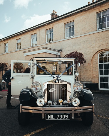 London, United Kingdom – October 02, 2022: A vertical view of a classic Rolls-Royce wedding car parked before a building