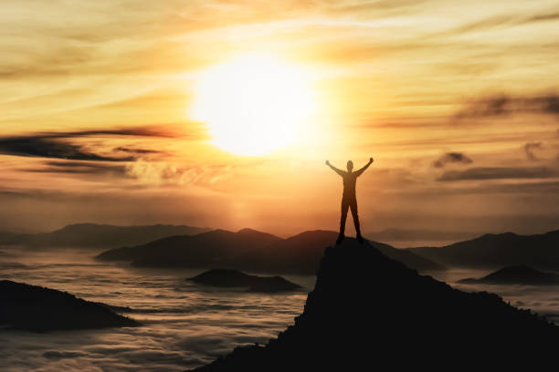 istock Silhouette man standing and raise two hand on peak stone rock in mountain and watching to sunrise fog, mist, sunset, sunlight. Misty valley. Man hike.Person silhouette stand. Mountain nature concept. 1453728414