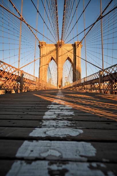 Vertical shot of the Brooklyn bridge in the early morning with sunshine on it in New York A vertical shot of the Brooklyn bridge in the early morning with sunshine on it in New York brooklyn bridge new york stock pictures, royalty-free photos & images