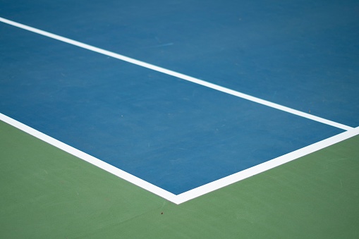 The left sideline of a blue tennis court with white lines, concept of a tennis match