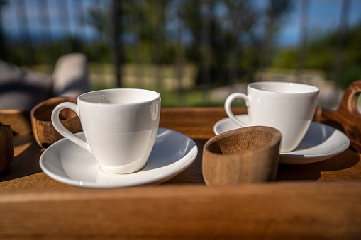 A closeup of two empty white coffee cups on a wooden tray