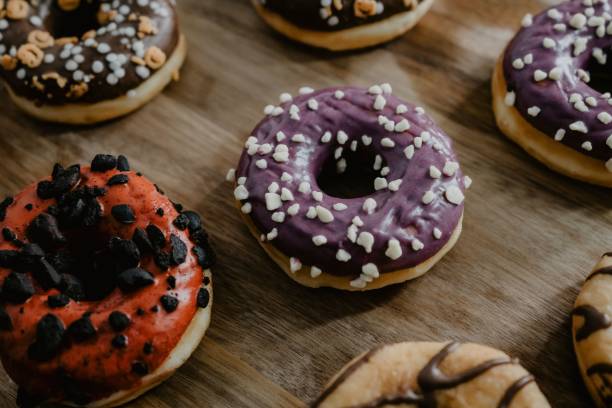 istock Freshly baked donuts, glazed with chocolate, differently decorated, served on a wooden cutting board 1453736718