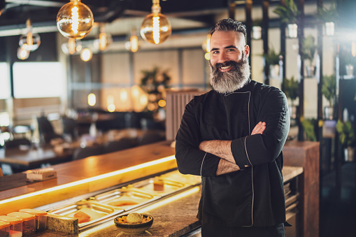 Portrait of cheerful sushi chef at sushi restaurant.