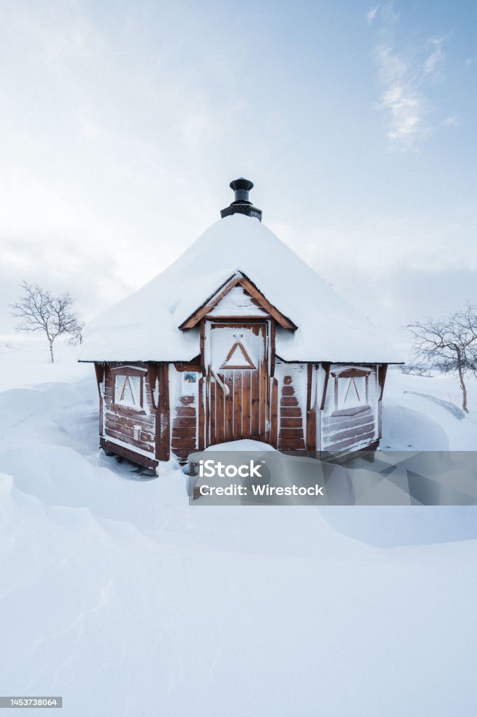 Lappish hut covered in snow Snow has surrounded a Lappish hut in Kilpisjarvi Lapland Blue Stock Photo