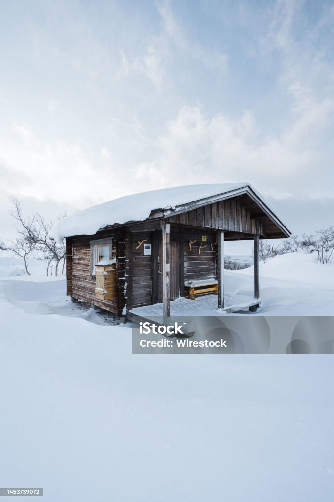 Hut with a porch in winter landscsape Small hut surrounded by snow in Finnish Lapland Architecture Stock Photo