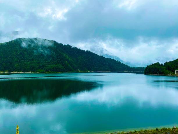 istock Beautiful shot of forested mountains and clouds reflected on a lake 1453739487