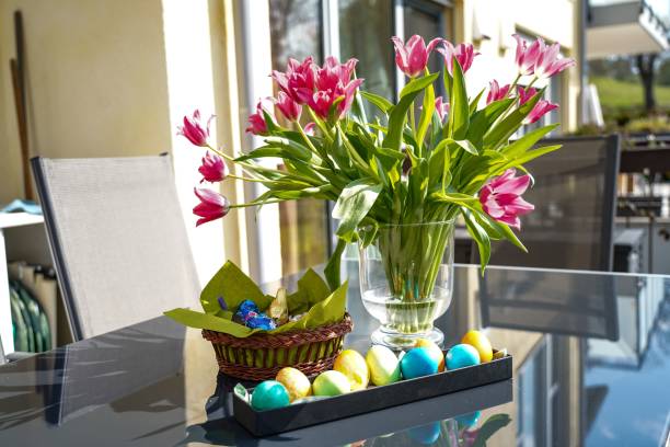 istock Colored eggs and pink tulips in vase on a sunny day 1453739865