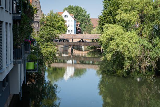 istock Bridge, trees, and buildings reflected on the Pegnitz river on a sunny day 1453739991