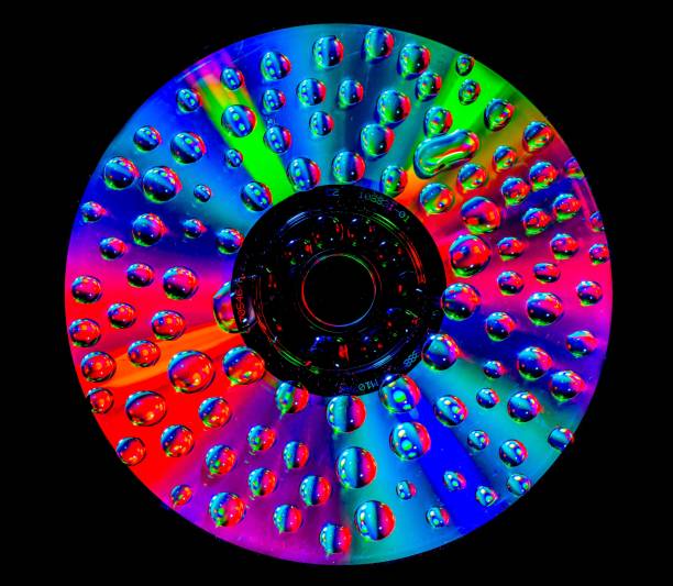 A closeup of small water droplets on a rainbow DVD disc on a black background