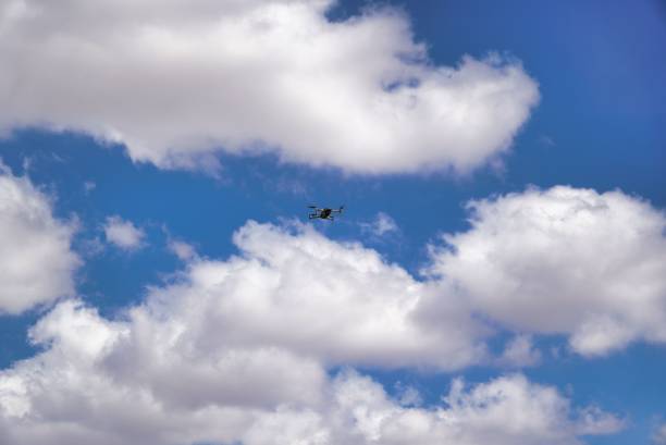 istock Low-angle view of a drone flying in the air against a cloudy blue sky 1453740742