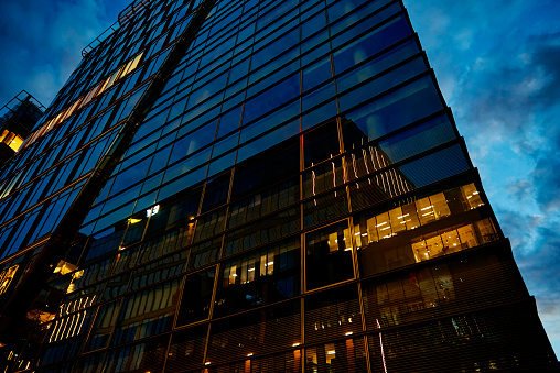 Office building facade with illuminated windows at night city. Warsaw city downtown district with skyscraper facade. Night city panorama