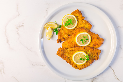 Breaded fish, baked and served with lemon. Common dab, edible flatfisch (Limanda limanda)