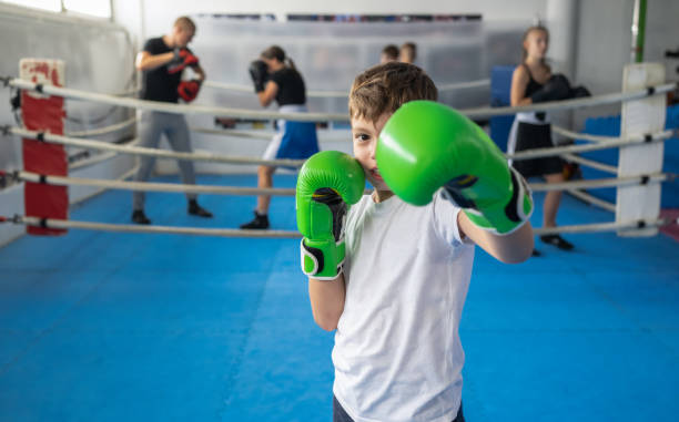 A Small Boy In Green Boxing Gloves Posing In Defended Stance stock photo