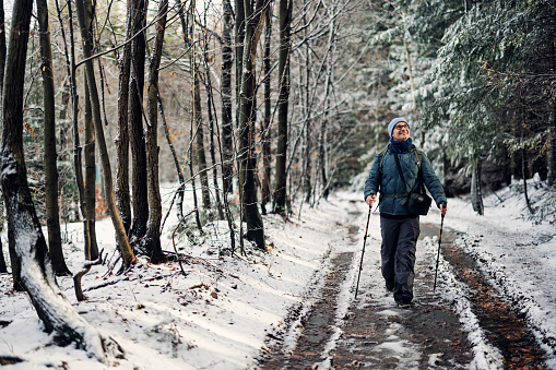 Mature man is hiking in the forest on a beautiful winter day.\nCanon R5