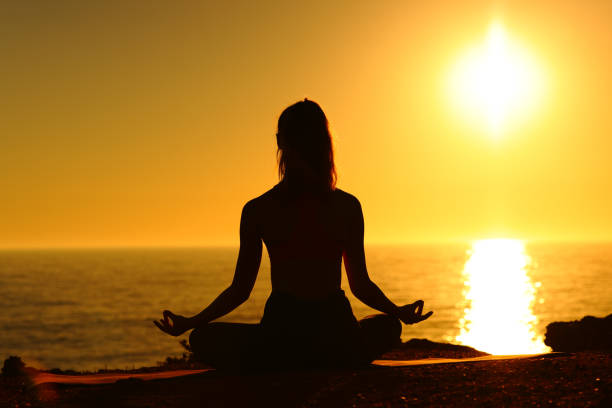 istock Yogi silhouette on the beach doing yoga 1453754370
