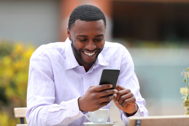 istock Happy black man checking mobile phone in a bar 1453754495