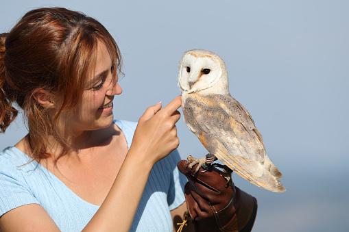 Happy affectionate falconer caressing a owl