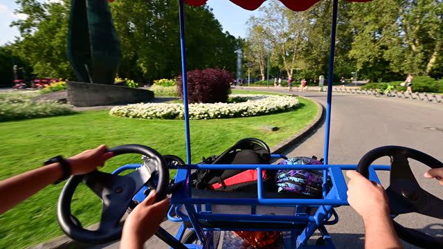 Budapest, Hungary, August 2022. Stunning POV footage from the driver's seat of a pedal quadricycle at Margaret Island. The two guys behind the wheel lead the vehicle.