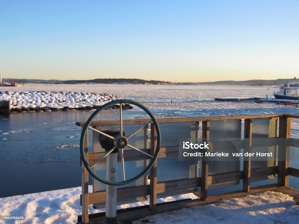 Ship steering wheel and a partially frozen Oslofjord in winter Ship steering wheel and a partially frozen Oslofjord  on a beautiful cold sunny day with blue sky. Beauty In Nature Stock Photo
