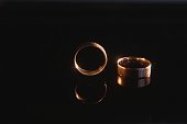 Elegant wedding rings for the bride and groom on a black background with highlights, macro, selective focus.
