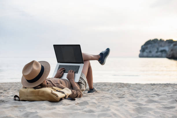 istock Young woman using laptop on a beach 1453758391