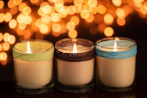 istock Burning white candle in glass jar on yellow blur background 1453764992