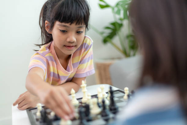 istock Little sibling girl playing chess at home. 1453767756