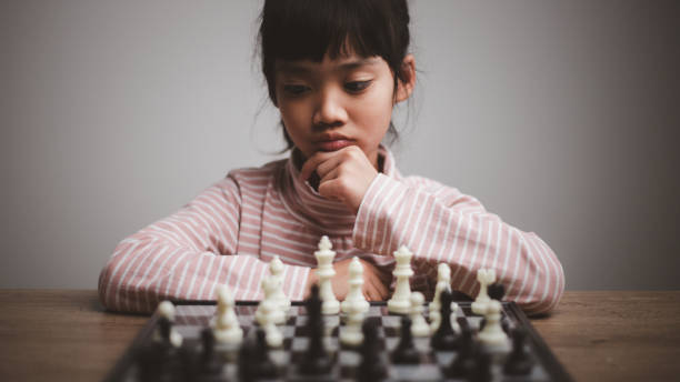 niña participando en una competición de ajedrez pensando en estrategia, hobby - chess skill concentration intelligence fotografías e imágenes de stock