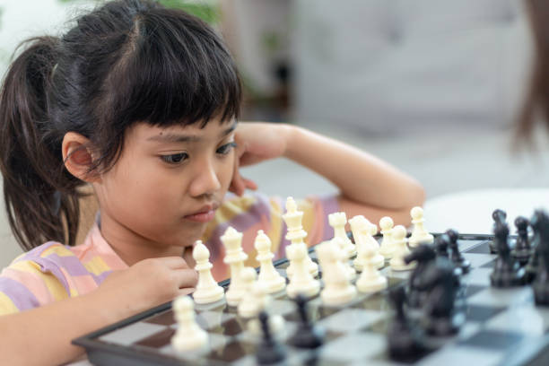 istock Little sibling girl playing chess at home. 1453767763