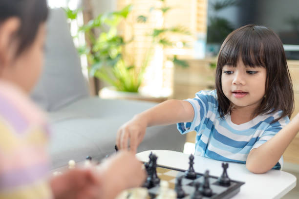 istock Little sibling girl playing chess at home. 1453767769