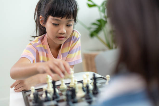 istock Little sibling girl playing chess at home. 1453767781