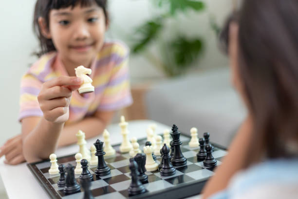 Little sibling girl playing chess at home. Little sibling girl playing chess at home. asian kid chess stock pictures, royalty-free photos & images