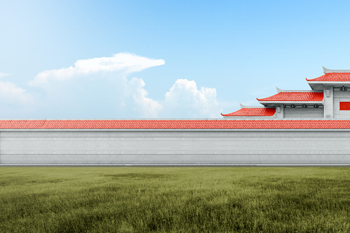 Chinese pavilion gate with red roof on the meadow with blue sky background