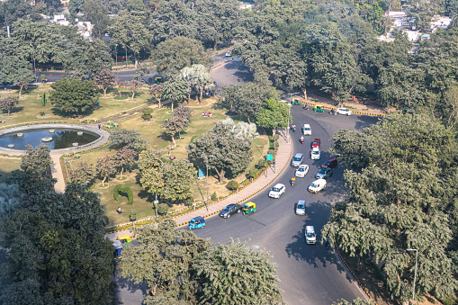 Stock photo showing view of traffic with motorcycles, cars and auto rickshaws driving around a roundabout in Delhi.