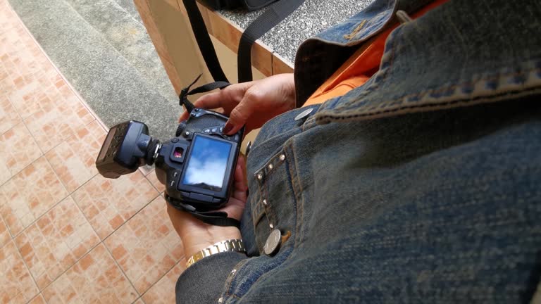 Asian senior woman holding a DSLR camera viewing images on the monitor. High Angle