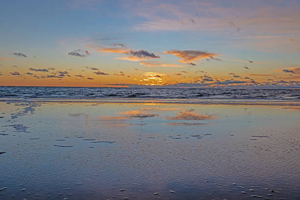 Sunset over the sea with reflections in the rising surf in winter
