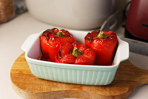 Stuffed red bell peppers in a ceramic pan freshly baked in the oven.
