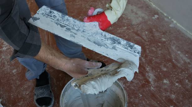 istock hands of a plasterer with two spatulas and mortar 1453779529
