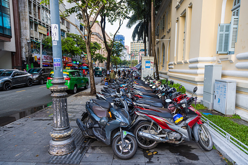 Ho Chi Minh City, Vietnam - November 07, 2022: Parking space for motor bikes and Scooter on the sidewalk at Saigon. Mopeds are the main mode of transportation in Ho Chi Minh City. Cityscape of Saigon
